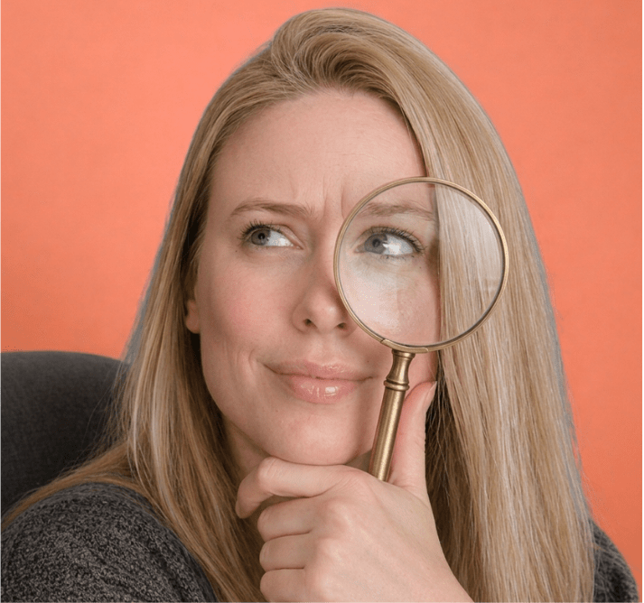 Hannah with a magnifying glass against the original orange background